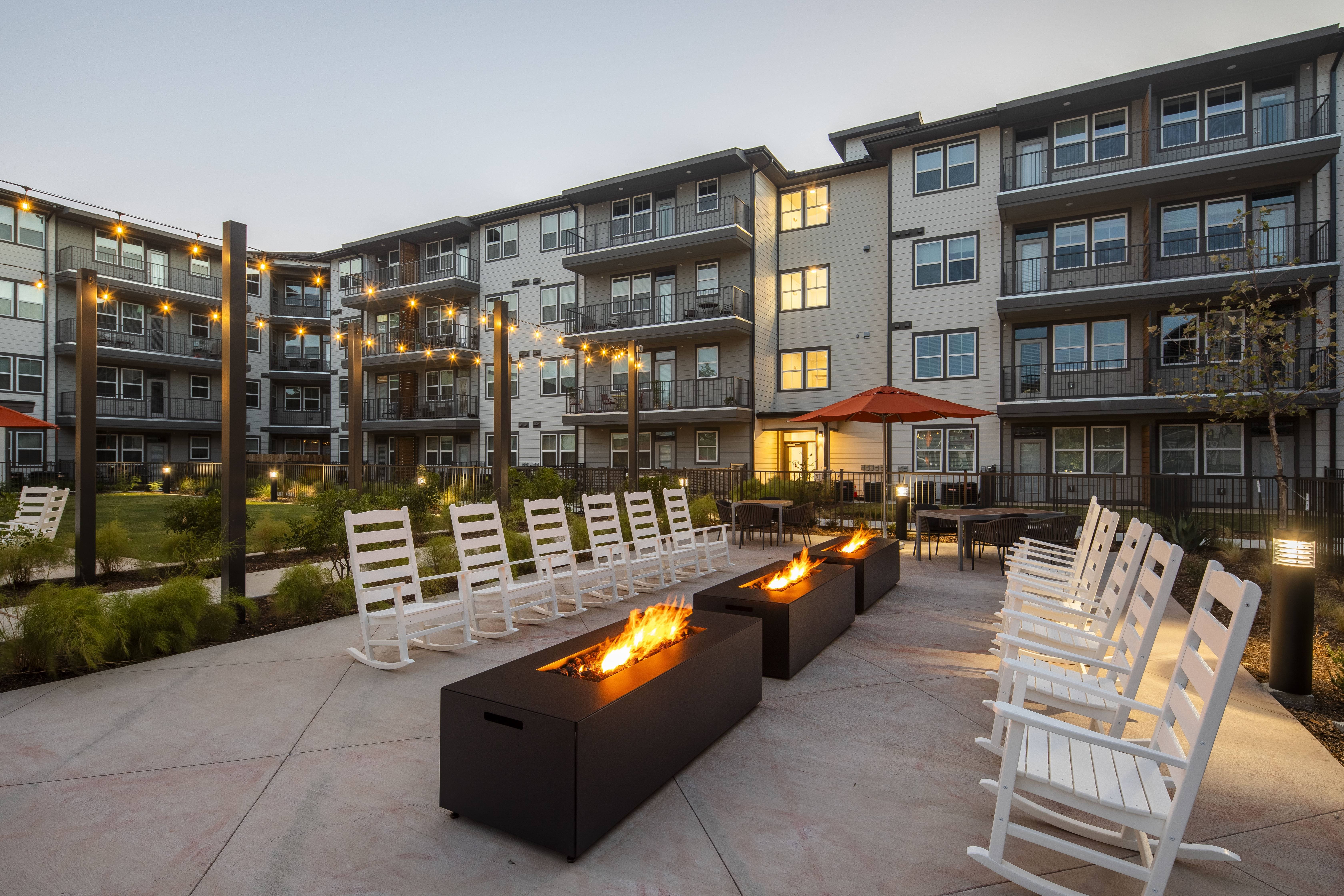 an outdoor patio with chairs and fire pits at a senior apartment community